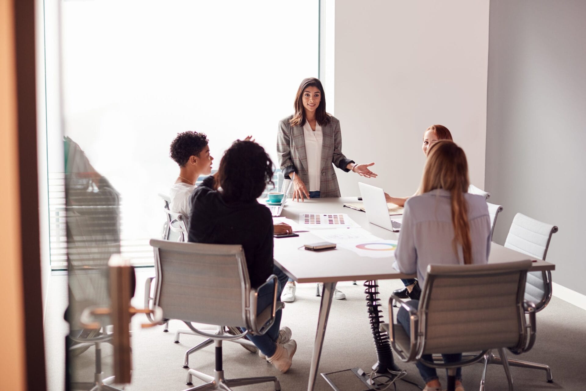Female Boss Gives Presentation To Team Of Young Businesswomen Meeting  Around Table In Modern Office | Sendero Consulting