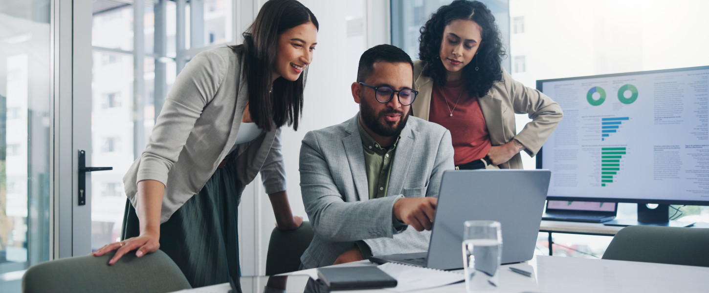 Three people working around a computer