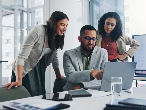 Three people working around a computer