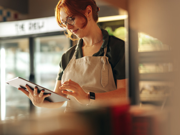 Grocery store employee standing with a tablet