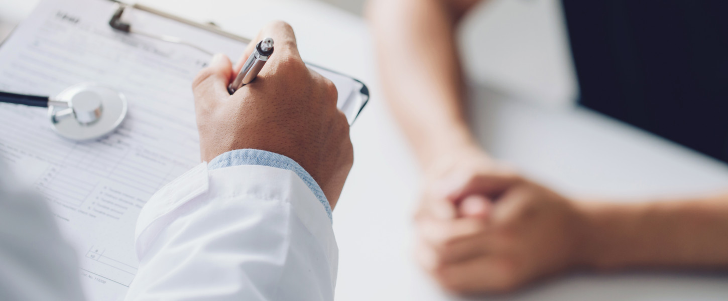 Doctor holding a clipboard and talking to a patient