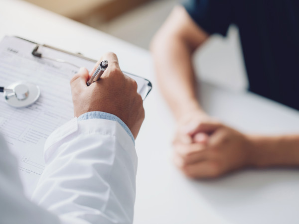 Doctor holding a clipboard and talking to a patient
